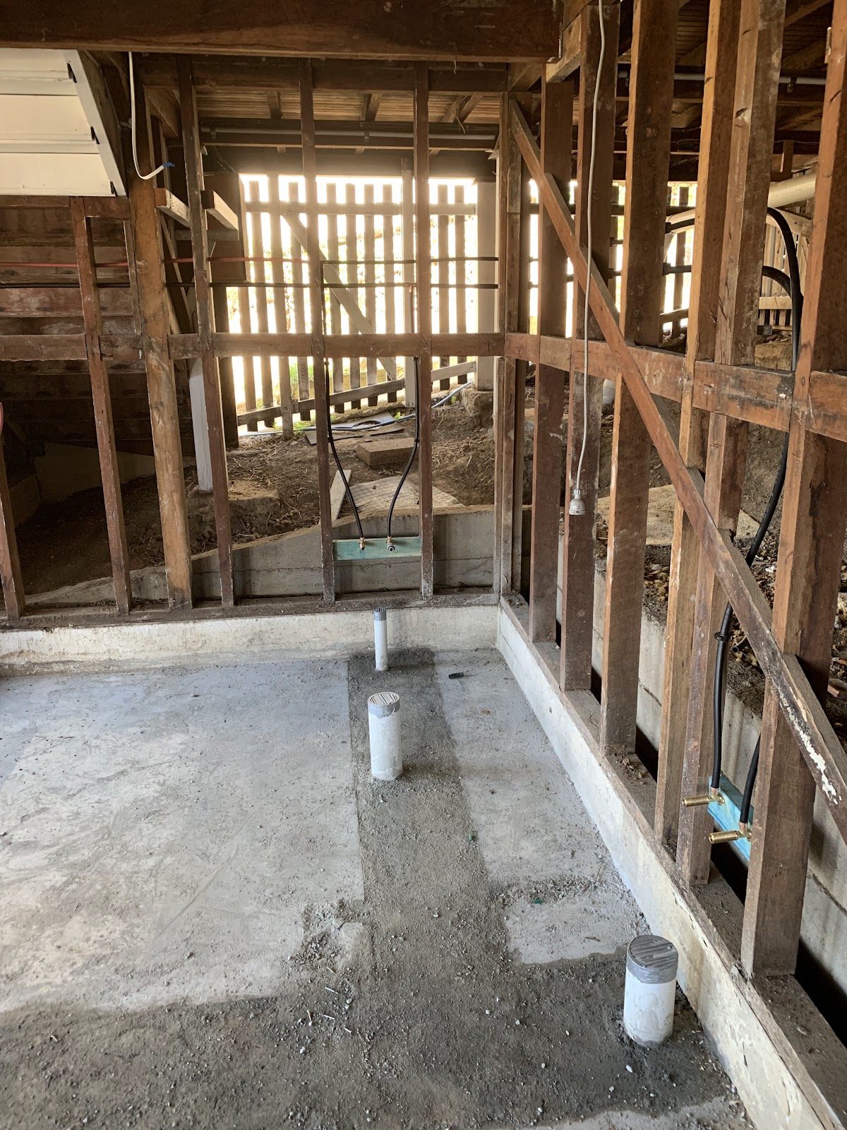 A bathroom stripped back to the frame with new plumbing stubs coming up through the slab