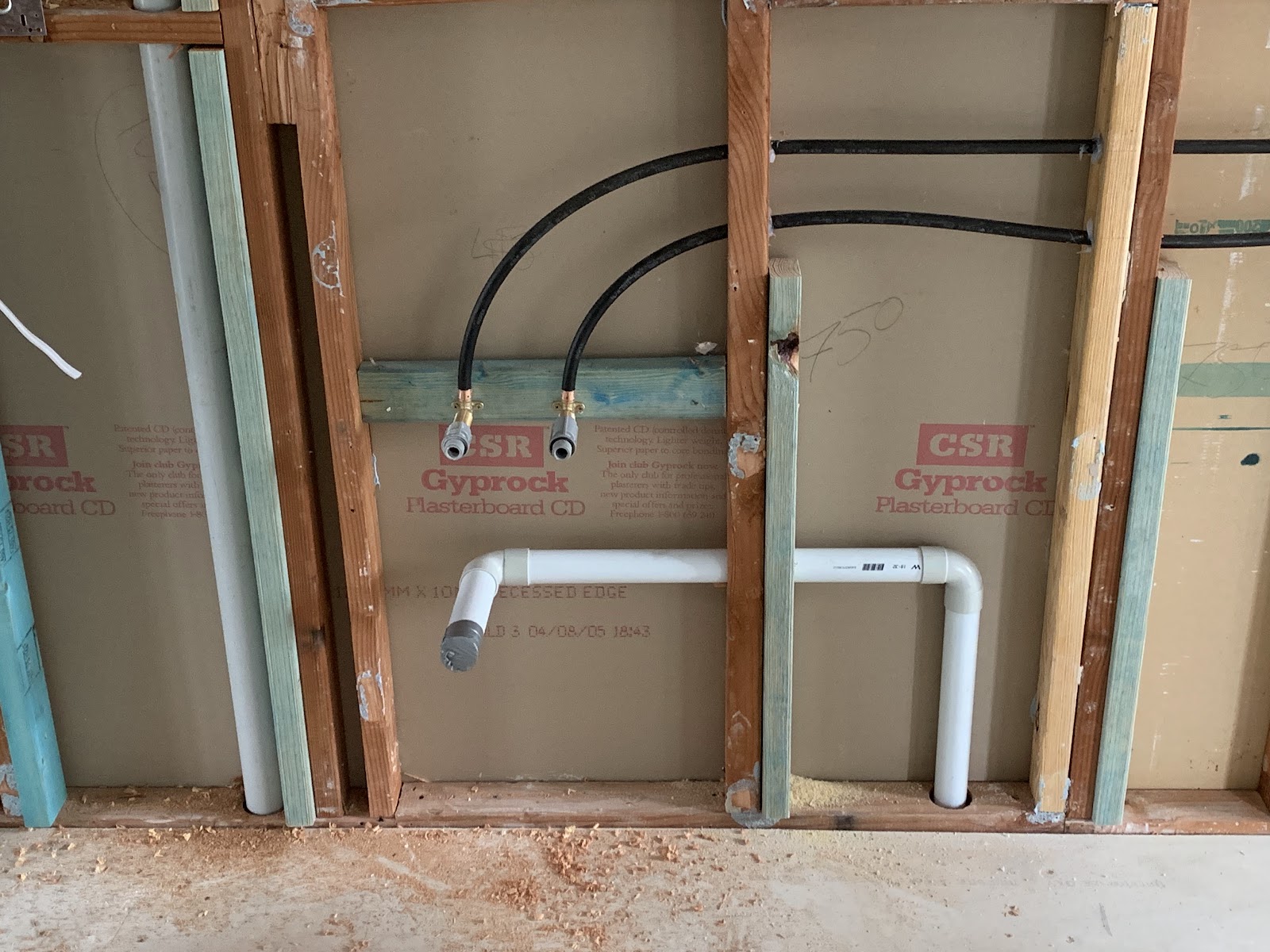 New hot and cold water pipes and a waste pipe run through a timber wall frame